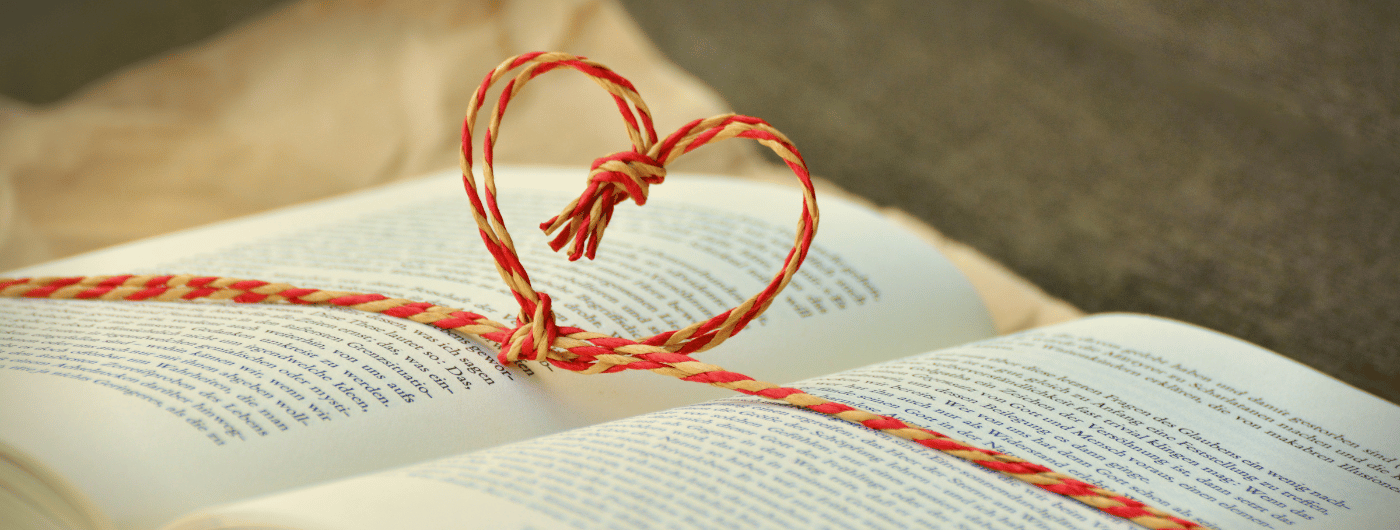 Heart made out of string on top of an open book.